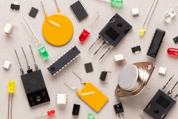 Electronic components on a beige background. There are microcontrollers, transistors, yellow and red LEDs, microcircuits, thyristors, capacitor. - obrazy, fototapety, plakaty