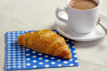 tasse de chocolat chaud et viennoiserie sur une table