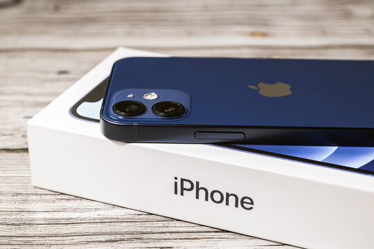 Saint Petersburg, Russia - November 28, 2020: Studio shot of brand new Apple iPhone 12 mini blue rear view on the box on wooden background. Unpacking purchase concept.