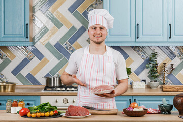 The cook shows fresh meat for cooking on a plate.