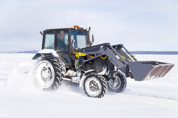 Snow removal vehicle on the road. Snow plow tractor is cleaning a city embankment after snowstorm...