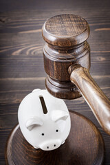 Judge wooden gavel is brought over piggy bank. Bank account arrest concept