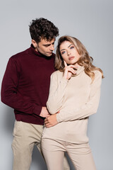  young couple in turtleneck jumpers posing isolated on grey