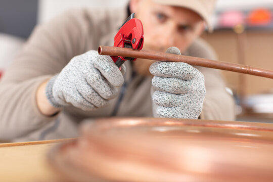 plumber cutting a copper pipe with a pipe cutter