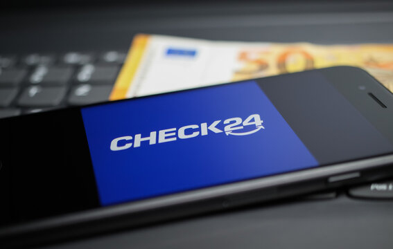 Viersen, Germany - April 9. 2020: Close up of mobile phone screen with logo lettering of Check24 comparison portal on computer keyboard, 50 Euro money background