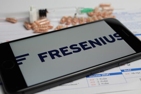 Viersen, Germany - April 9. 2020: Close up of mobile phone screen with logo lettering of Fresenius pharmaceutical company, blurred pills and lab sheet background