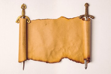 Scroll of old paper with burnt edges stretched on the blades of knightly swords, isolation on a white background. Copy space
