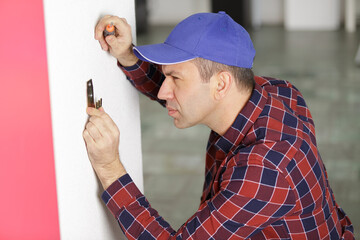 man repairs and paints the wall
