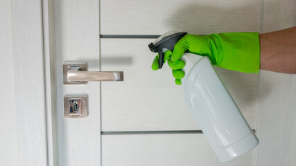Cleaning door knob with alcohol spray for Covid-19 Coronavirus prevention