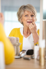 beautiful portrait of an elder woman making up with lipstick