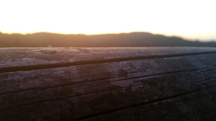 Close-up shot of wooden beam with sunset in the background