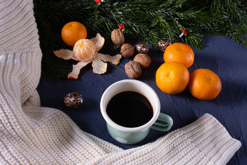 fir branches on a table near tangerines, white sweater, coffee mug and nuts