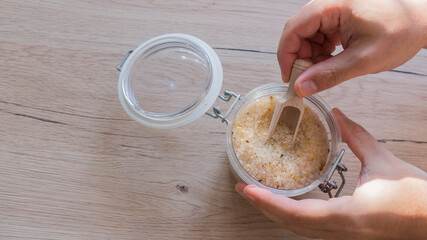 bath salt in glass with male hand on wooden table