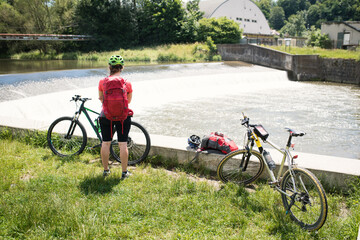 Young female athlete relaxing near a river view after cycling