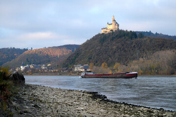 Der Rhein mit Niedrigwasser bei Braubach mit Binnenschiff und Marksburg - Stockfoto