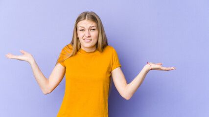 Young blonde woman isolated on purple background confused and doubtful shrugging shoulders to hold a copy space.