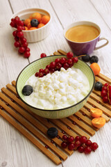 Light breakfast with cottage cheese. Homemade grained cottage cheese with berries on a white wooden table - 396631839