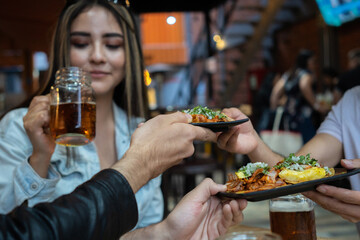 friends eating and sharing pastor tacos in a restaurant