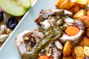 Pork loin stuffed with apples, walnuts, carrots, pistachios and chestnuts. On the side, potatoes in chunks. Lomo relleno.