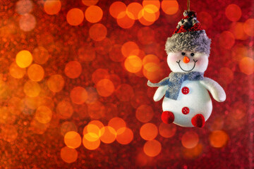 Funny white snowman on a red bokeh background. Bright red horizontal winter Christmas background. Winter holiday.