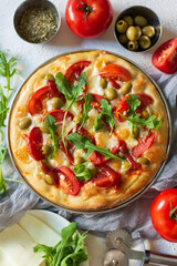 Top view of delicious pizza Margarita a dish of yeast dough stuffed with tomatoes, mozzarella, olives, ketchup, arugula on a light textured background