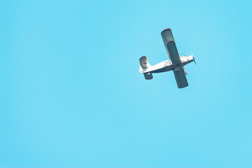 Old retro plane flies in the blue sky.