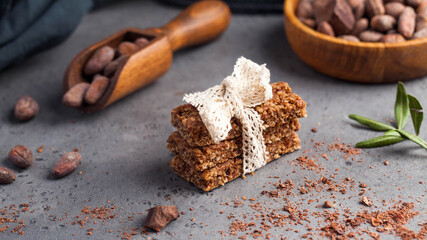 Granola bar with chocolate on a gray background with cocoa beans. Healthy snack, vegan snack
