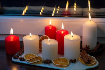 Burning candles on the windowsill of the evening winter window.