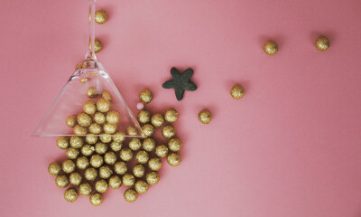 Cocktail glass and  gold decorative  balls on pink background. Party composition. Minimalistic concept.