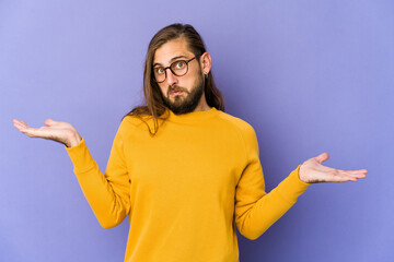 Young man with long hair look confused and doubtful shrugging shoulders to hold a copy space.