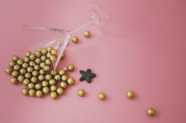 Cocktail glass and  gold decorative  balls on pink background. Party composition. Minimalistic concept.