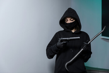 Thief broke into the apartment. House robbery by woman in a black jacket and black mask black gun...