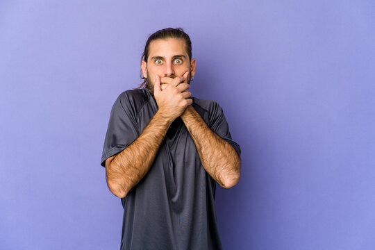 Young man with long hair look shocked pointing with index fingers to a copy space.