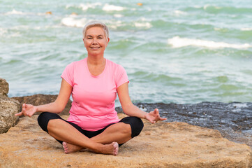 Fototapeta na wymiar Sports mid age woman meditating at the beach and smiling