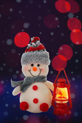One toy snowman and a lantern with a burning candle on a blue blurry background with bokeh. Christmas and New year celebration concept