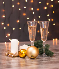 Shiny background with gold Christmas decorations and champagne glasses. Christmas and New Year greeting card.