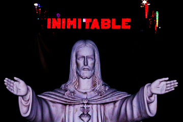 Estatua de Jesucriste con "INIMITABLE" al fondo.