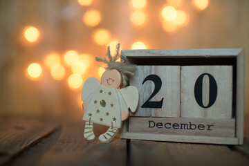 Cube wooden calendar showing date on 20th December with Angel over bokeh background. Advent calendar, Christmas background, Copy space