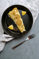 Fried baked mackerel trachurus with onions and dried herbs in an old frying pan in a towel with a fork. rustic rustic style. Top view, gray concrete background, place for text