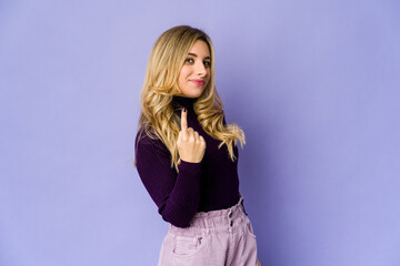 Fototapeta premium Young caucasian blonde woman pointing with finger at you as if inviting come closer.
