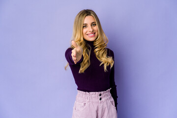Fototapeta premium Young caucasian blonde woman stretching hand at camera in greeting gesture.