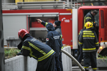 A photo of a firefighters from behind as they rest after putting out a large fire.