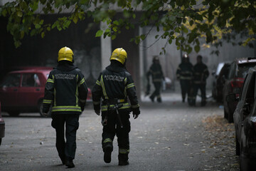 A photograph of firefighters walking away, after putting down a large fire in city.