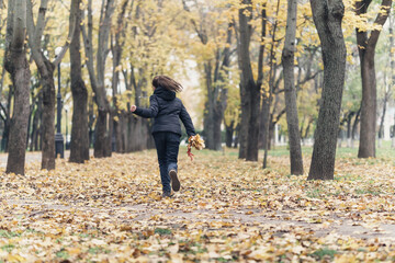 Fototapeta premium a girl running through the park and enjoys autumn, beautiful nature with yellow leaves