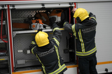 Two firefighters taking necessary equipment from the fire truck in hurry before they start off a rescue mission in Belgrade, Serbia.