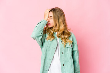 Young caucasian blonde woman forgetting something, slapping forehead with palm and closing eyes.