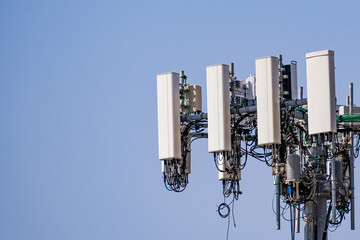 Close up of telecommunications cell phone tower with wireless communication antennas; blue sky...