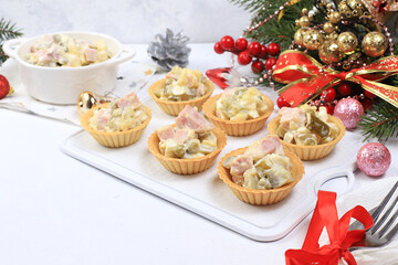 Christmas new year dishes, traditional festive olivier salad with fir branches and cones and decorations on a light table, dish design idea, selective focus, place for text