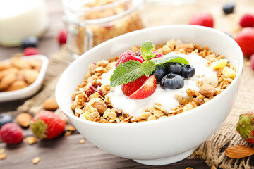 Tasty granola with fresh berries on brown wooden background
