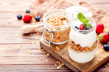Tasty granola with cream and berries on brown wooden background